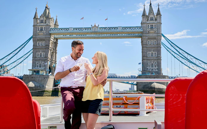 Guests enjoying drinks on a cruise with Tower Bridge in the background, London.