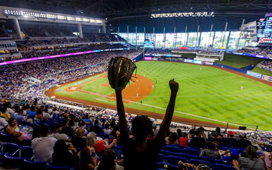 Fan cheering at a Miami Marlins baseball game in a packed stadium.
