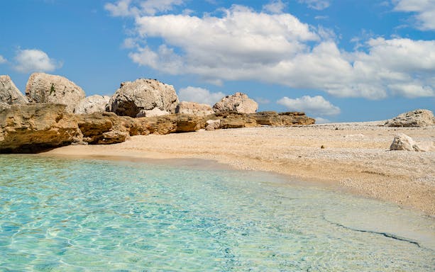 Cala Mariolu beach with clear turquoise water and rocky shoreline in Sardinia.