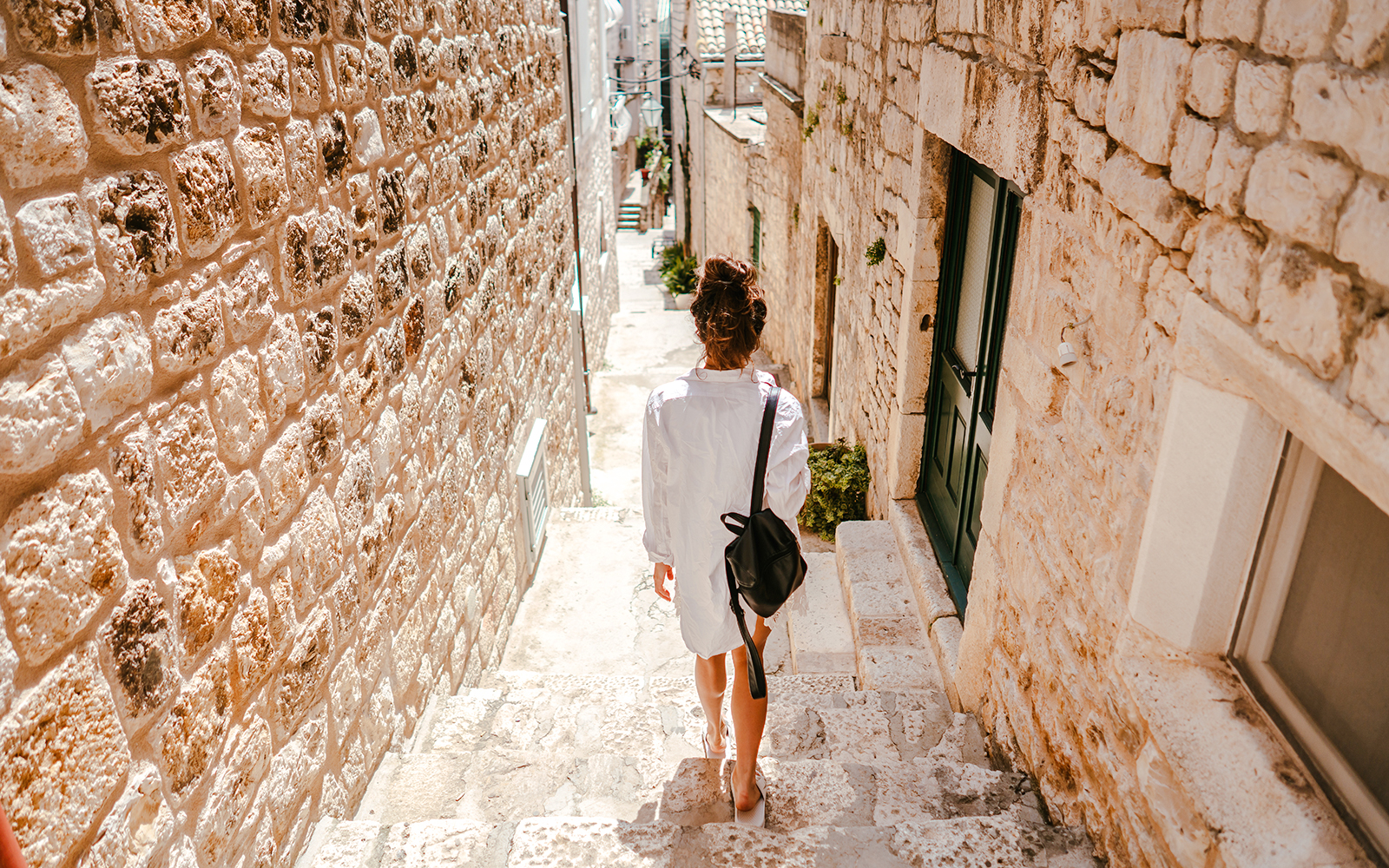 Young girl walking through ancient stone street in historic European town.
