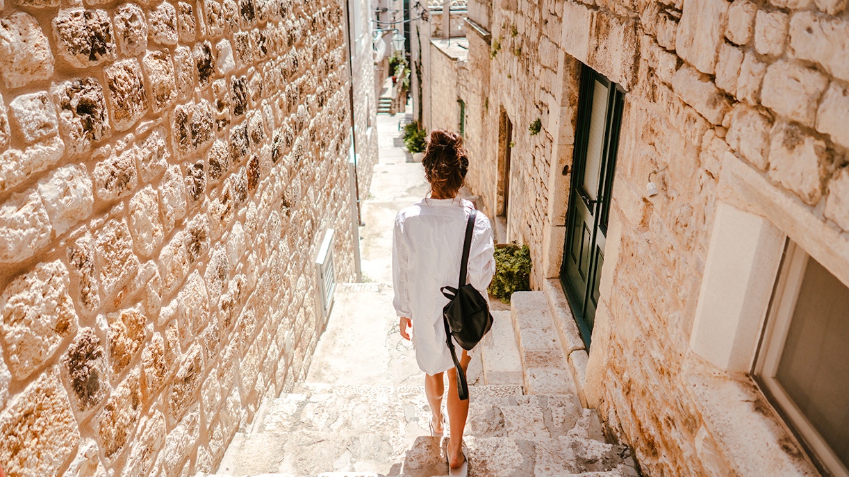 Young girl walking through ancient stone street in historic European town.
