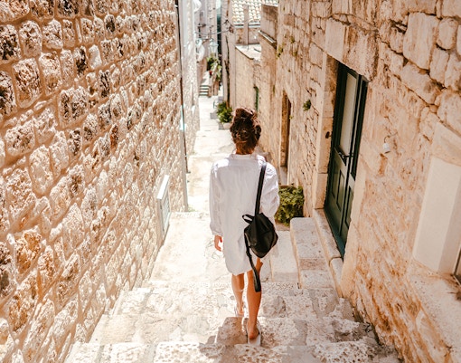 Young girl walking through ancient stone street in historic European town.