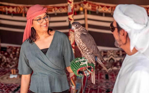 Woman holding trained eagle at Bedouin Culture Safari, Dubai.
