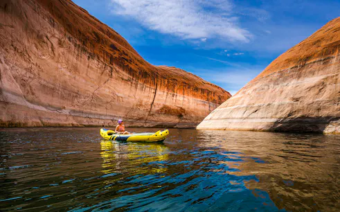 Kayaker paddling through narrow canyon walls on Lake Powell.