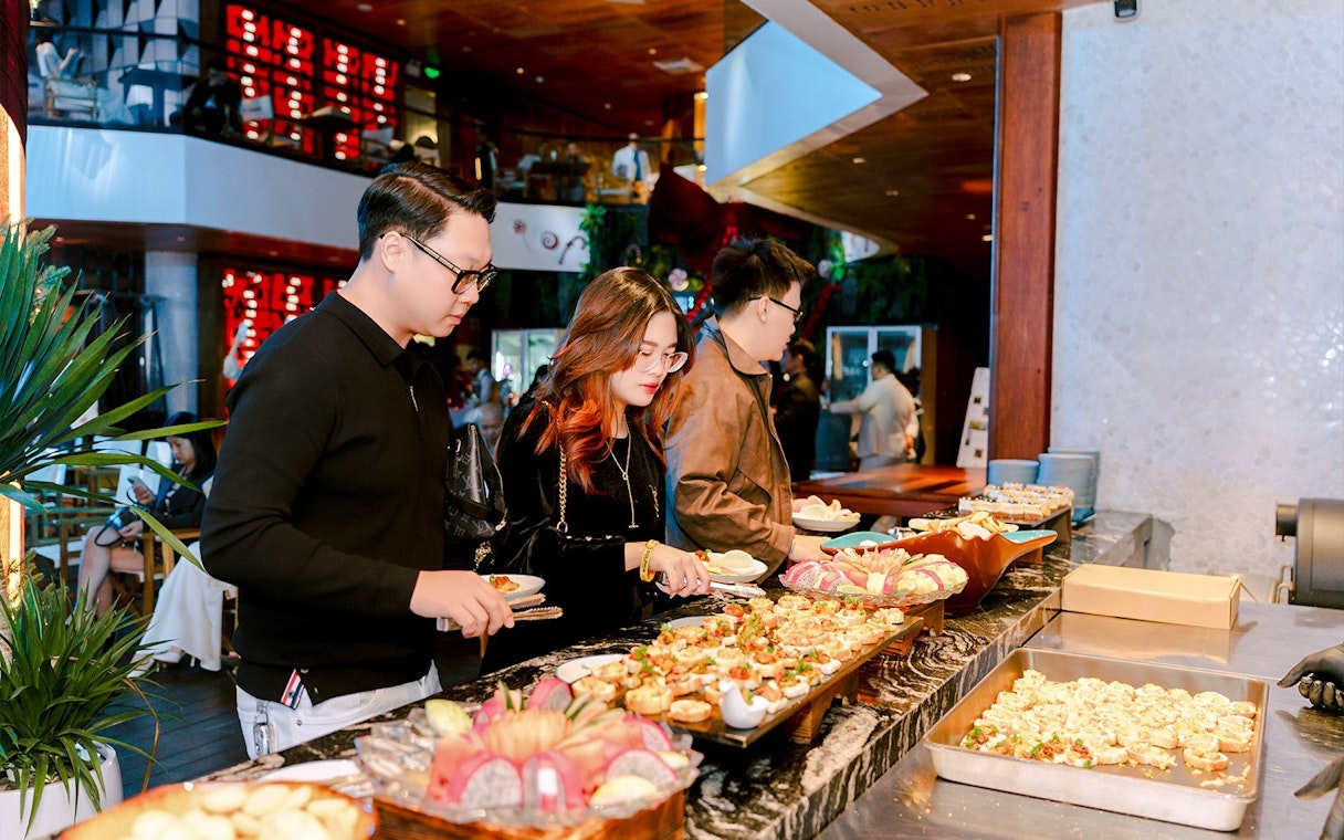 Guests selecting dishes at a dinner buffet in a restaurant setting.