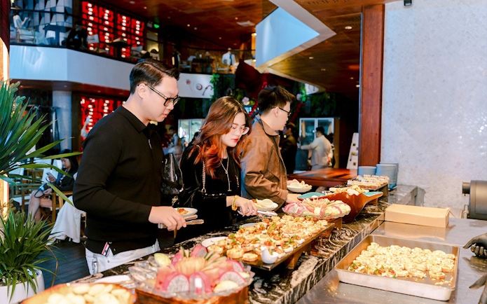 Guests selecting dishes at a dinner buffet in a restaurant setting.