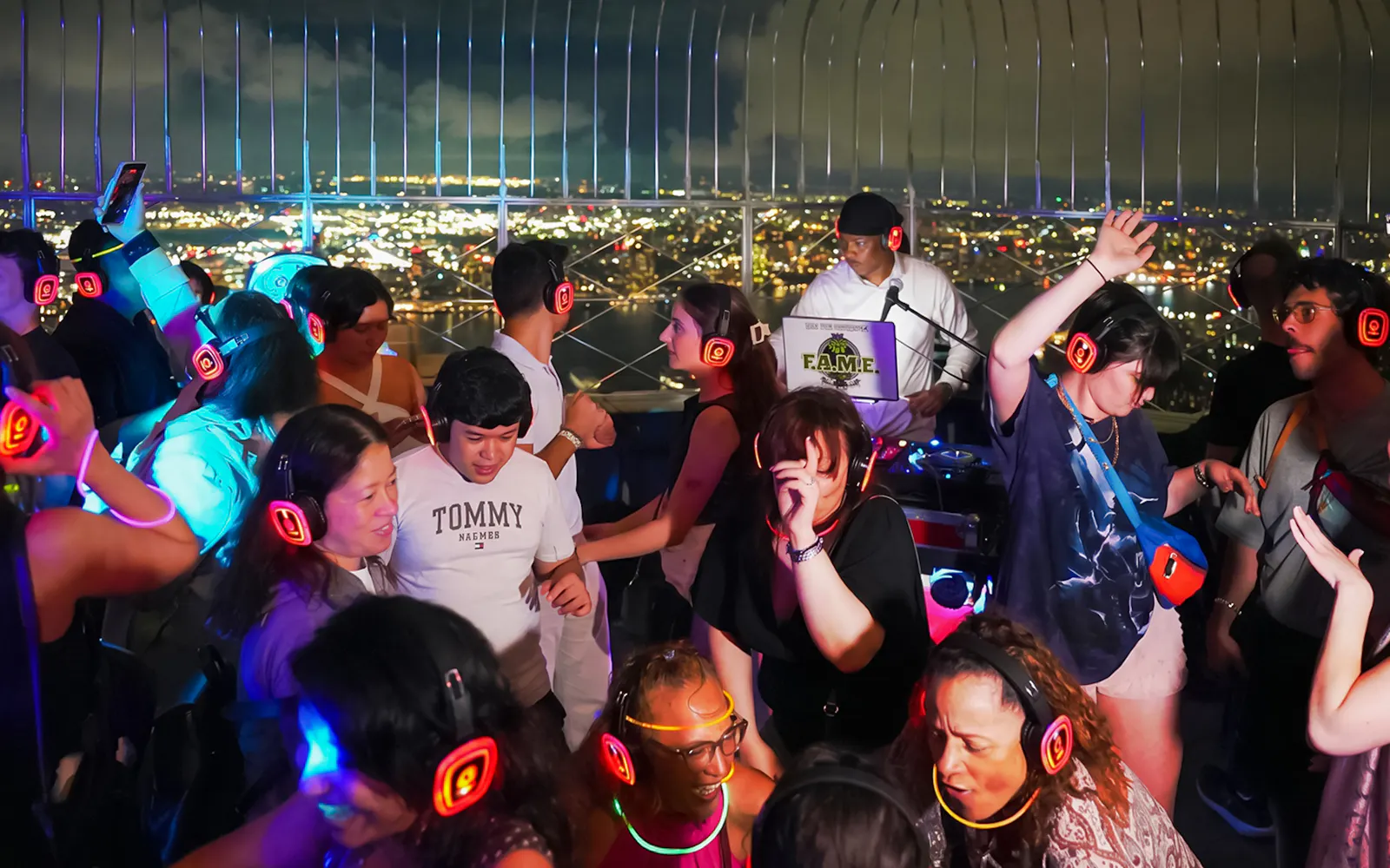 Silent disco on Empire State Building Observation Deck with people dancing and wearing headphones.