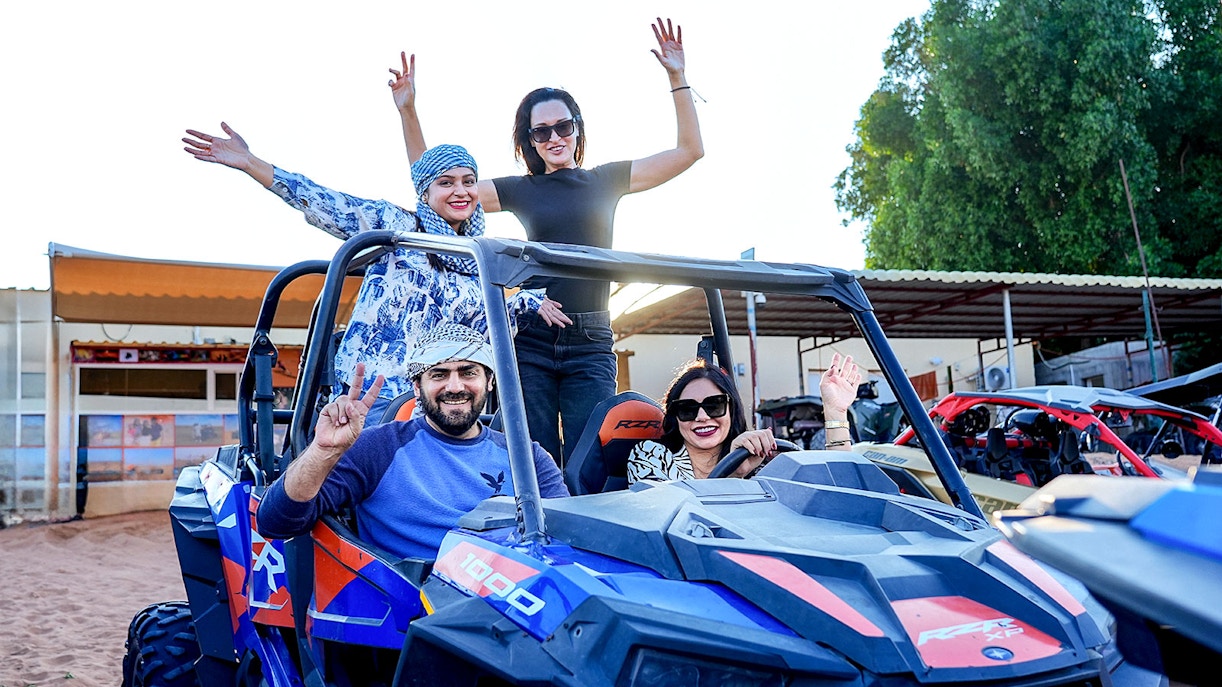 People enjoying dune bashing in a desert safari with off-road vehicles.