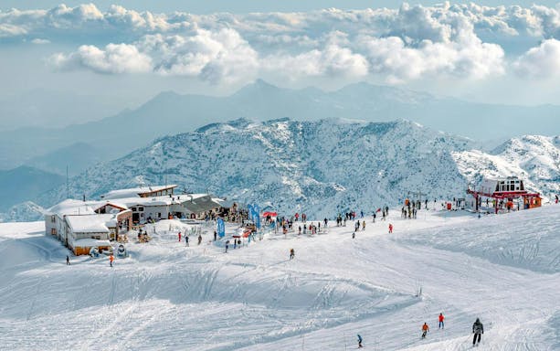 Skiers enjoying slopes at El Colorado Ski Resort, Chile, with snowy Andes mountains in the background.