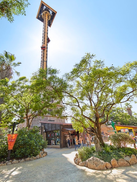 Hurakan Condor ride at PortAventura surrounded by trees and visitors.