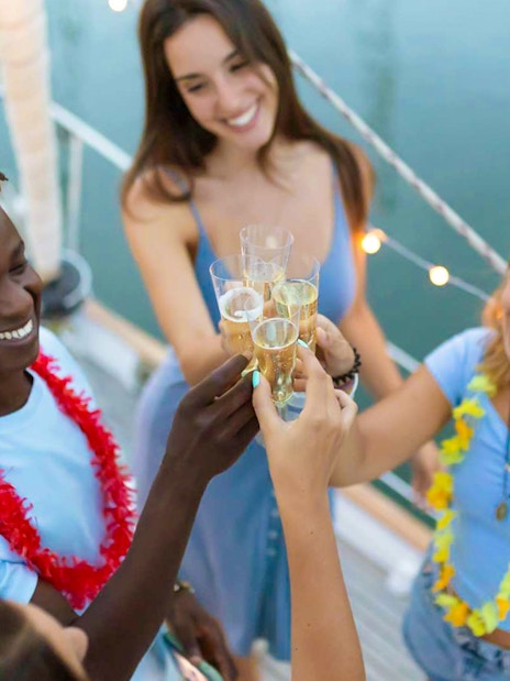 Guests toasting on a boat during Athens Riviera night party with wine and snacks.