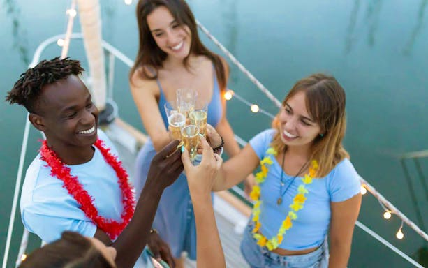 Guests toasting on a boat during Athens Riviera night party with wine and snacks.
