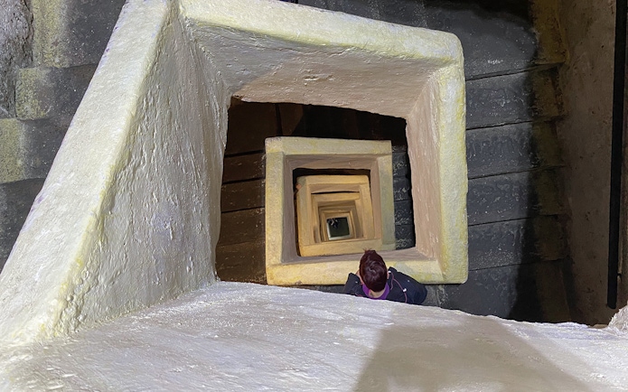 Naples Underground staircase with person descending through square stone passage.