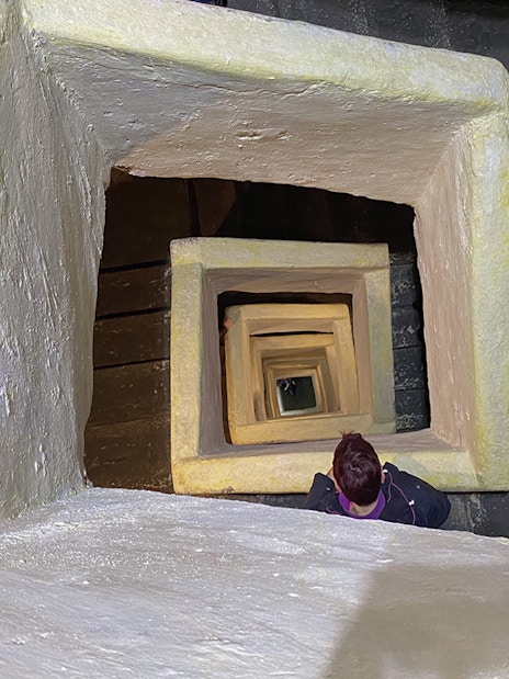 Naples Underground staircase with person descending through square stone passage.