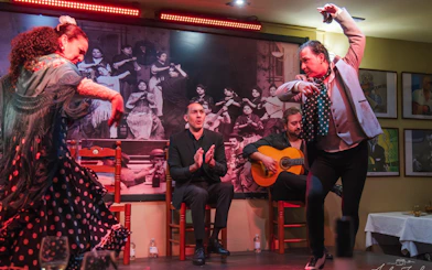 Flamenco dancers performing at Tablao La Cantaora, Seville with guitarist and clapping audience.