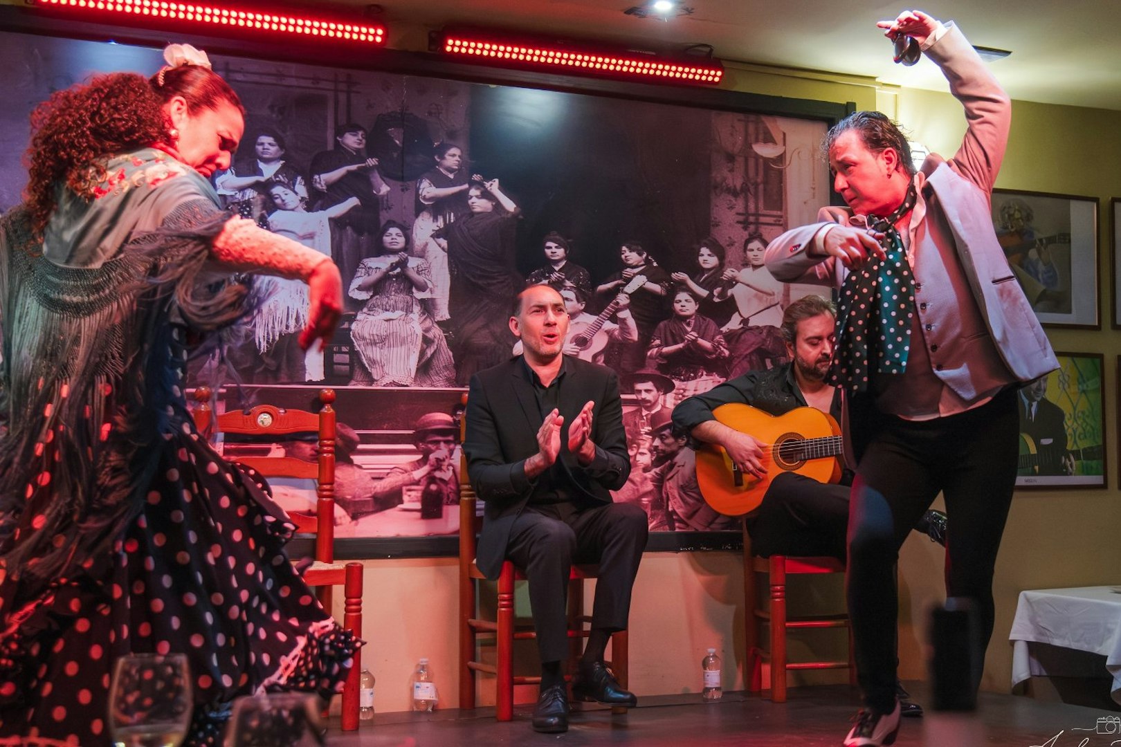 Flamenco dancers performing at Tablao La Cantaora, Seville with guitarist and clapping audience.