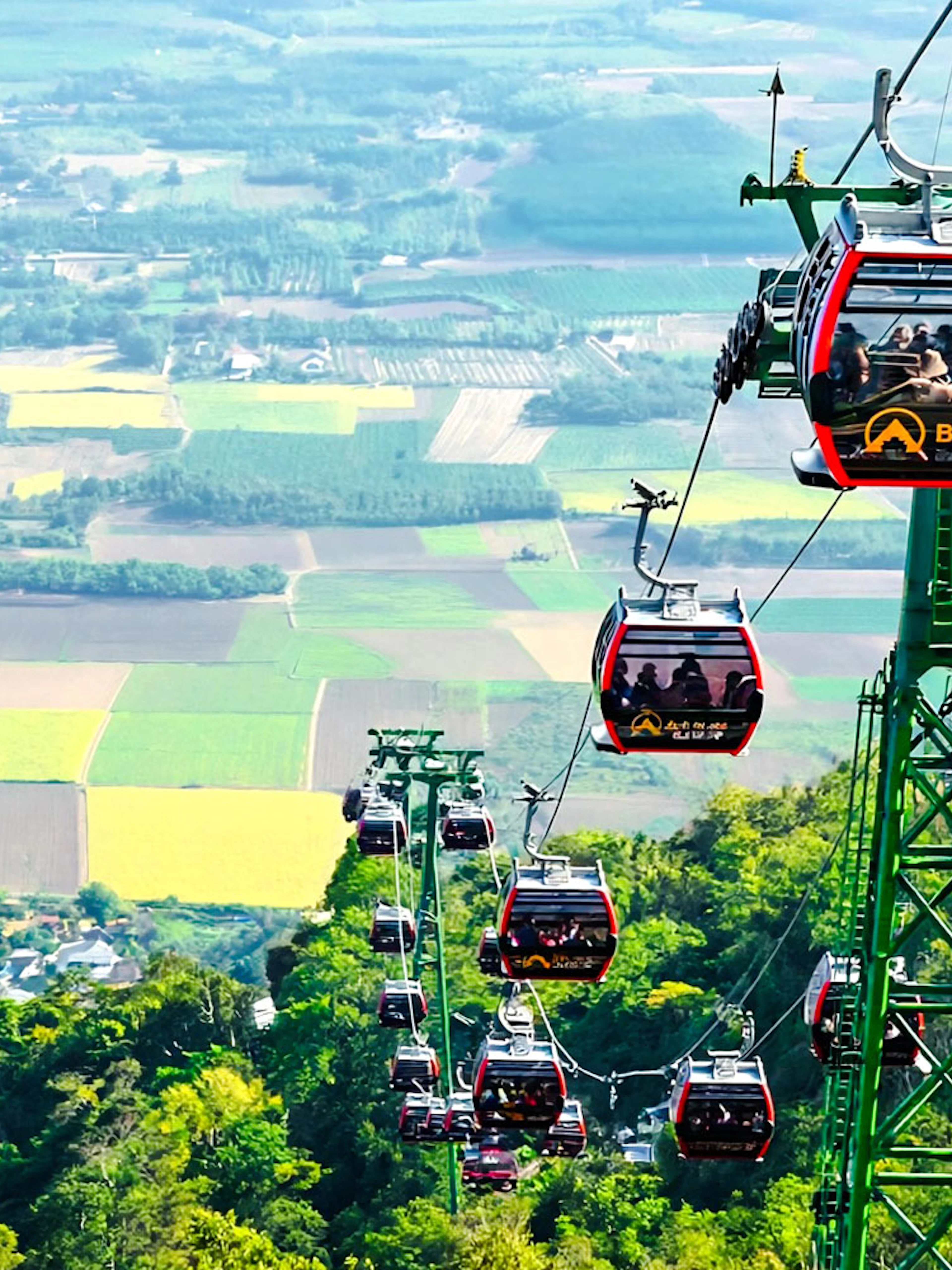 Cable cars ascending Ba Den Mountains with scenic landscape views.