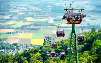 Cable cars ascending Ba Den Mountains with scenic landscape views.