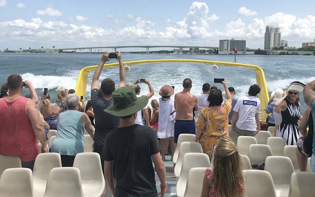 Tourists on the Sea Screamer boat ride at Clearwater Beach, capturing views of the water and skyline.