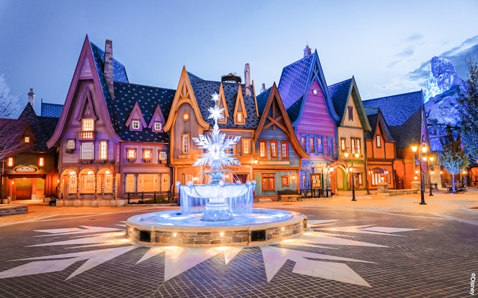 Colorful village scene with illuminated fountain at Disneyland Paris.