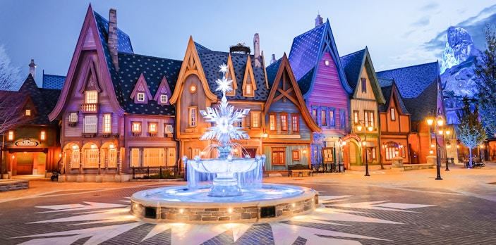 Colorful village scene with illuminated fountain at Disneyland Paris.