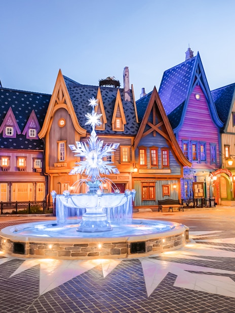 Colorful village scene with illuminated fountain at Disneyland Paris.