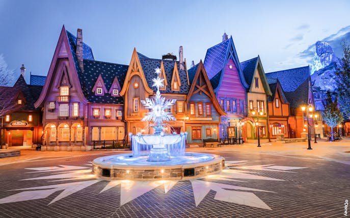 Colorful village scene with illuminated fountain at Disneyland Paris.