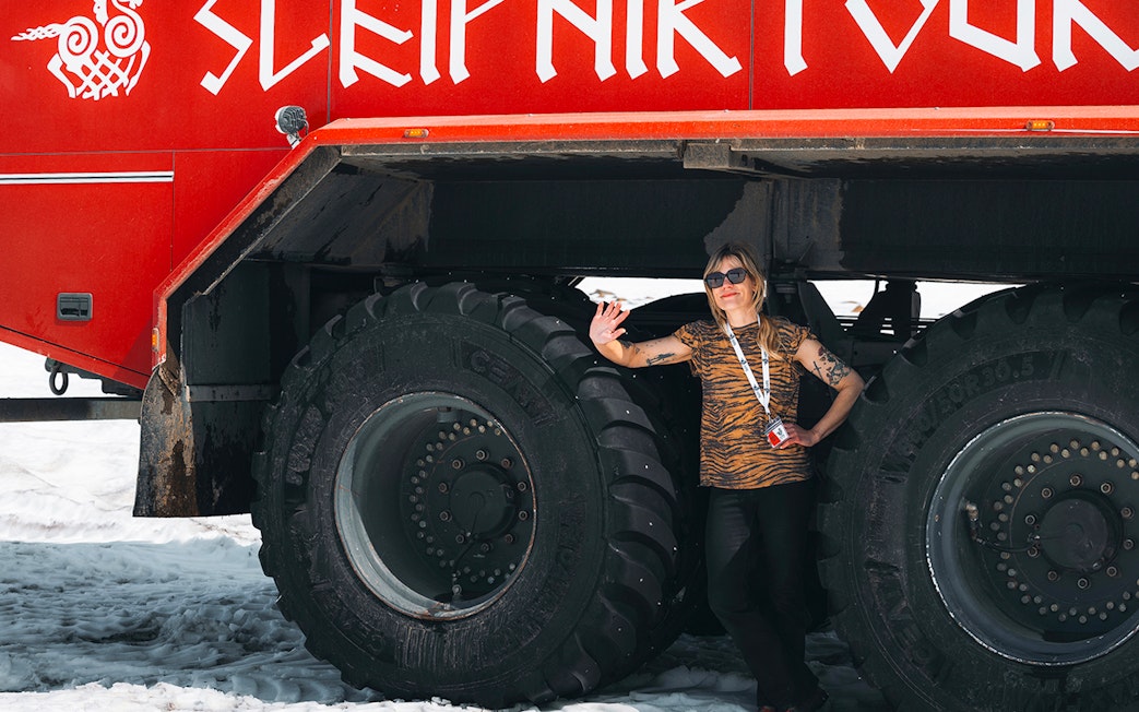 Red Monster truck on Langjökull Glacier Tour from Gullfoss with a person standing beside it.