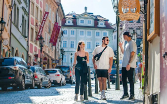 Guests walking on a cobblestone street near Prague Castle, surrounded by historic buildings.