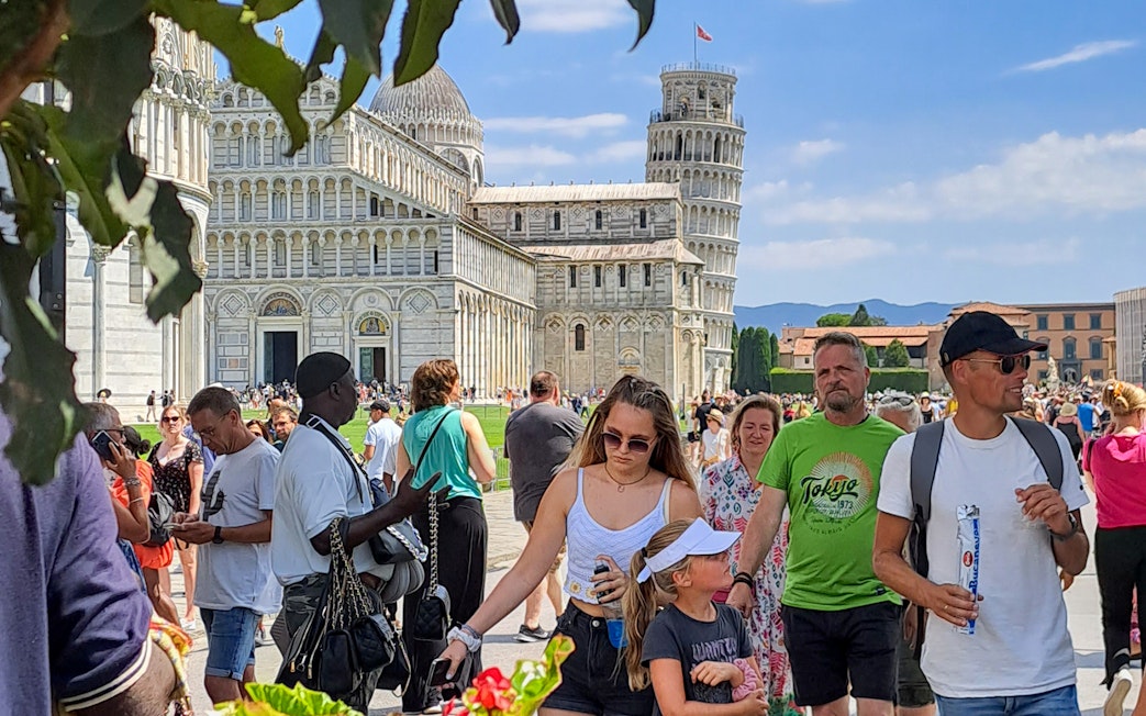 Tourists walking near Pisa Cathedral and Leaning Tower on a guided tour in Pisa, Italy.