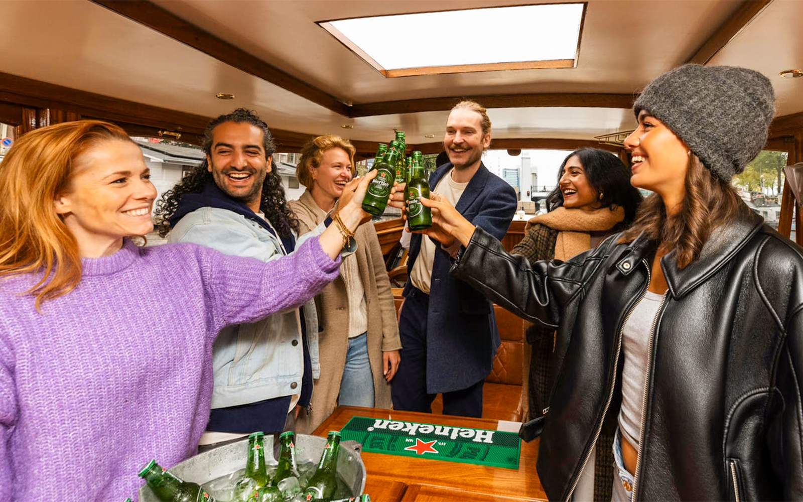 Guests toasting with beer on the Heineken Flagship Canal Cruise in Amsterdam.