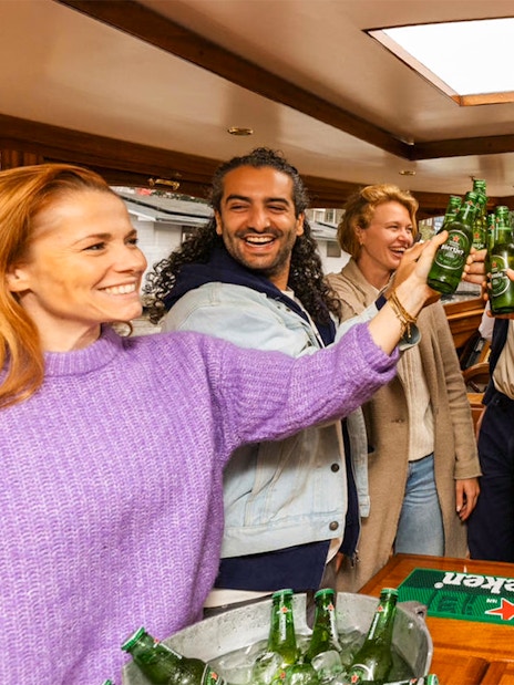 Guests toasting with beer on the Heineken Flagship Canal Cruise in Amsterdam.