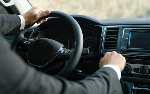 Chauffeur driving a luxury vehicle for professional transfers.