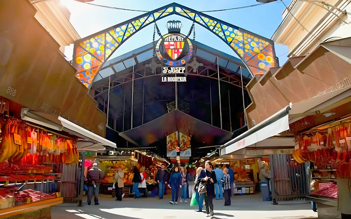 Entrance to La Boqueria food market with people shopping in Barcelona, Spain.