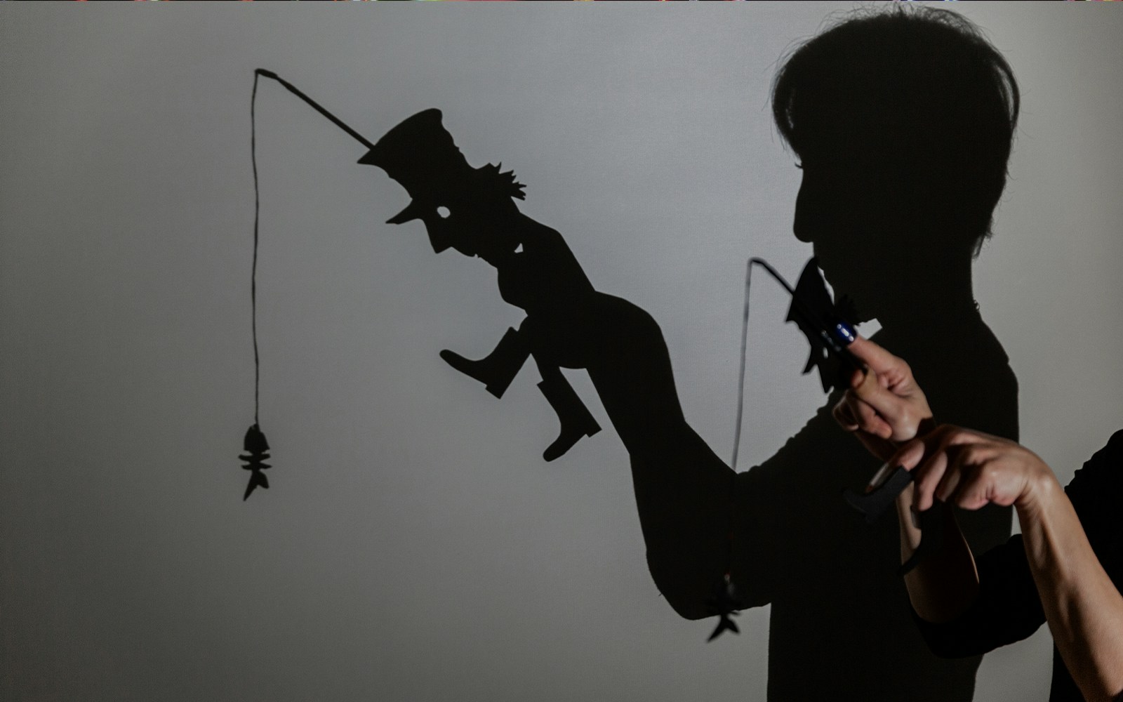 Shadow puppetry performance with fishing rod silhouette.
