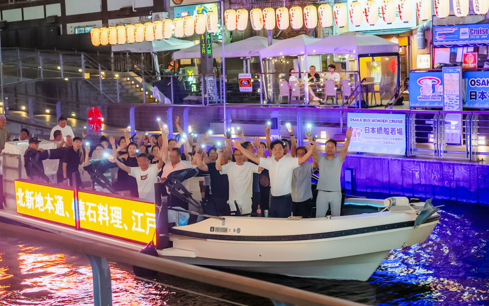 Group enjoying Osaka Dotonbori River Cruise at night with illuminated lanterns.