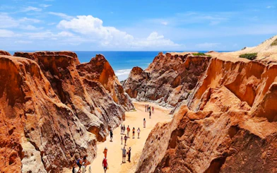 Visitors walking through colorful cliffs at Canoa Quebrada, East Coast, Brazil.