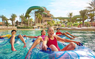 Tourists enjoying water slides at Aquaventure Waterpark, Dubai, with Lost Chambers Aquarium combo tickets.