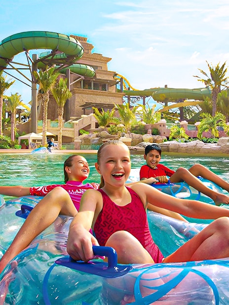Tourists enjoying water slides at Aquaventure Waterpark, Dubai, with Lost Chambers Aquarium combo tickets.