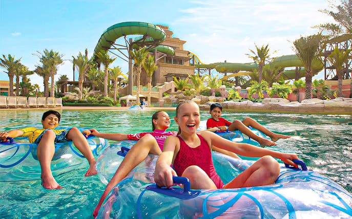 Tourists enjoying water slides at Aquaventure Waterpark, Dubai, with Lost Chambers Aquarium combo tickets.