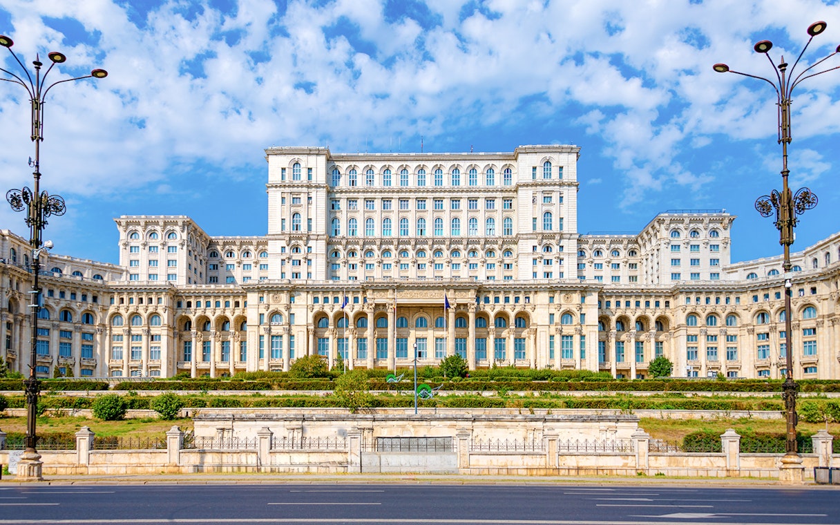 Palace of Parliament in Bucharest with ornate facade and clear blue sky.