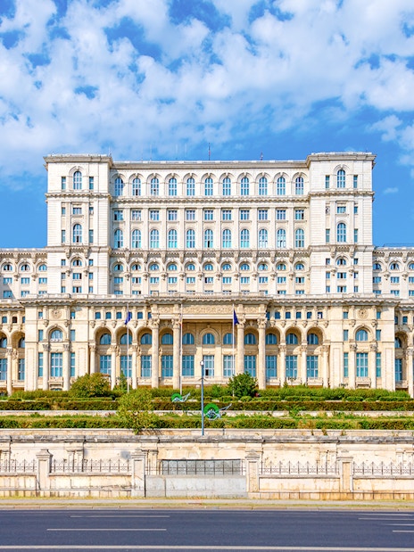 Palace of Parliament in Bucharest with ornate facade and clear blue sky.