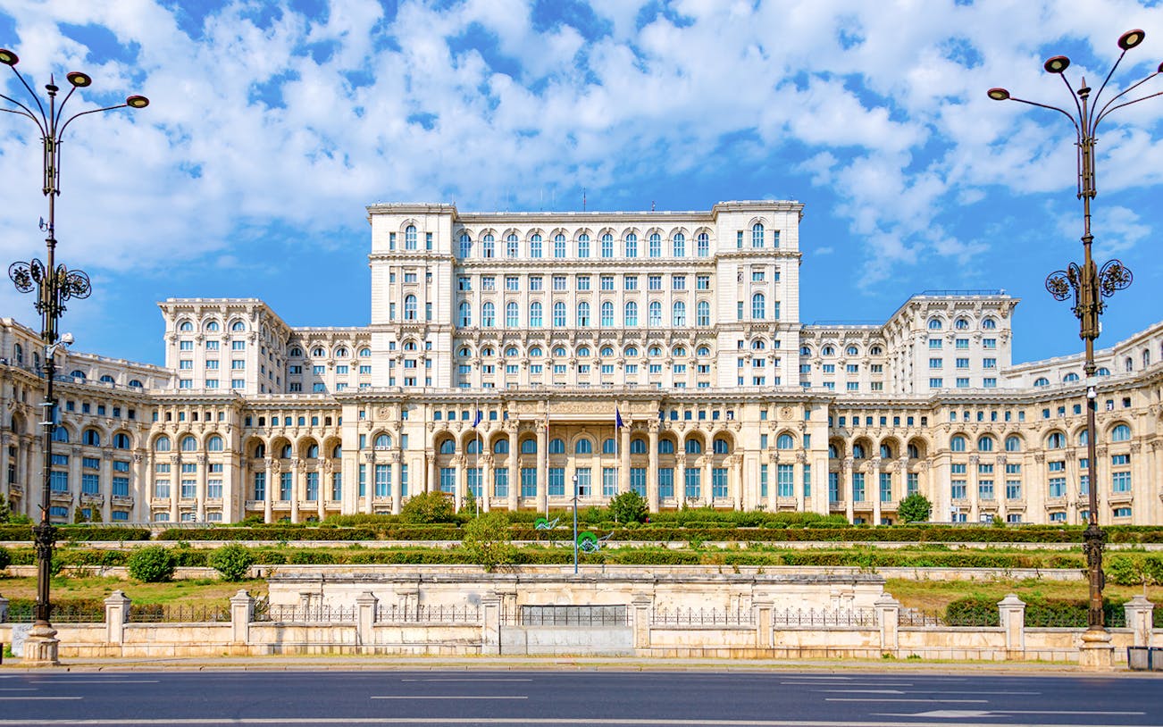 Palace of Parliament in Bucharest with ornate facade and clear blue sky.