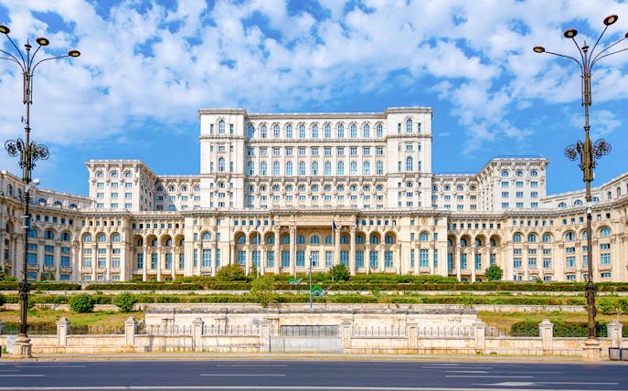 Palace of Parliament in Bucharest with ornate facade and clear blue sky.