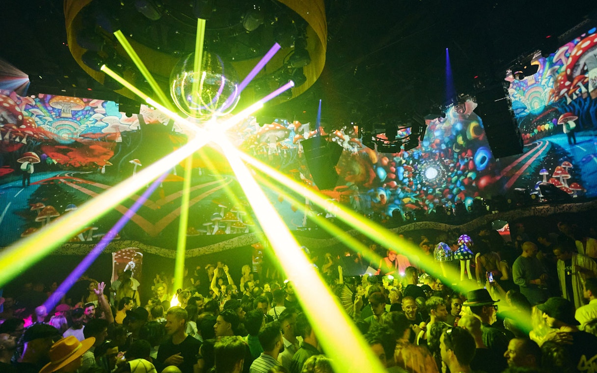 Crowd enjoying vibrant light show at TRIP Club Chinois with colorful psychedelic visuals.