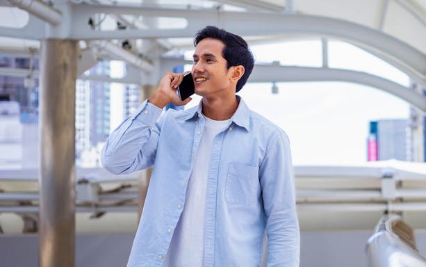 Man using phone with Thailand cityscape in background, promoting 15/30 days Unlimited Data eSIM.