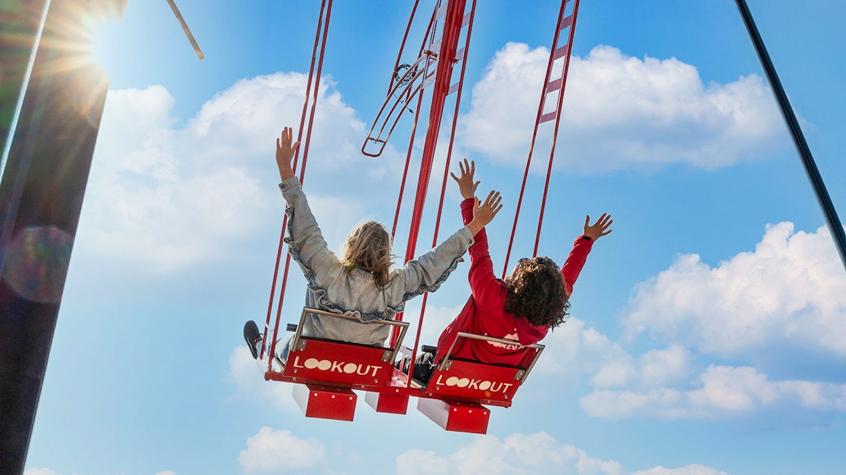 Visitors enjoying the swing at ADAM Lookout Over the Edge in Amsterdam with city skyline views.