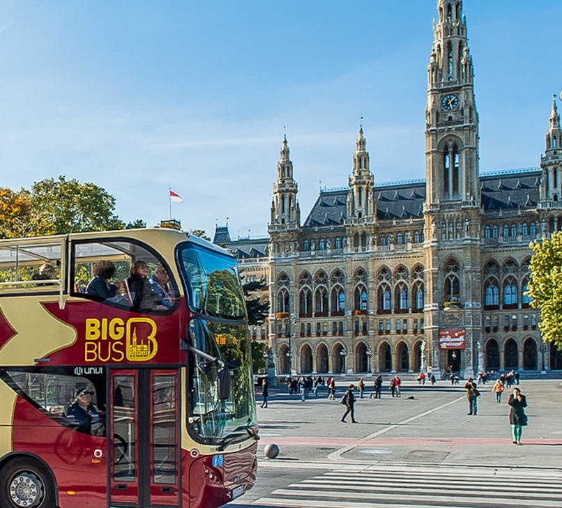 Vienna cityscape with Big Bus Vienna tour passing by historic buildings.