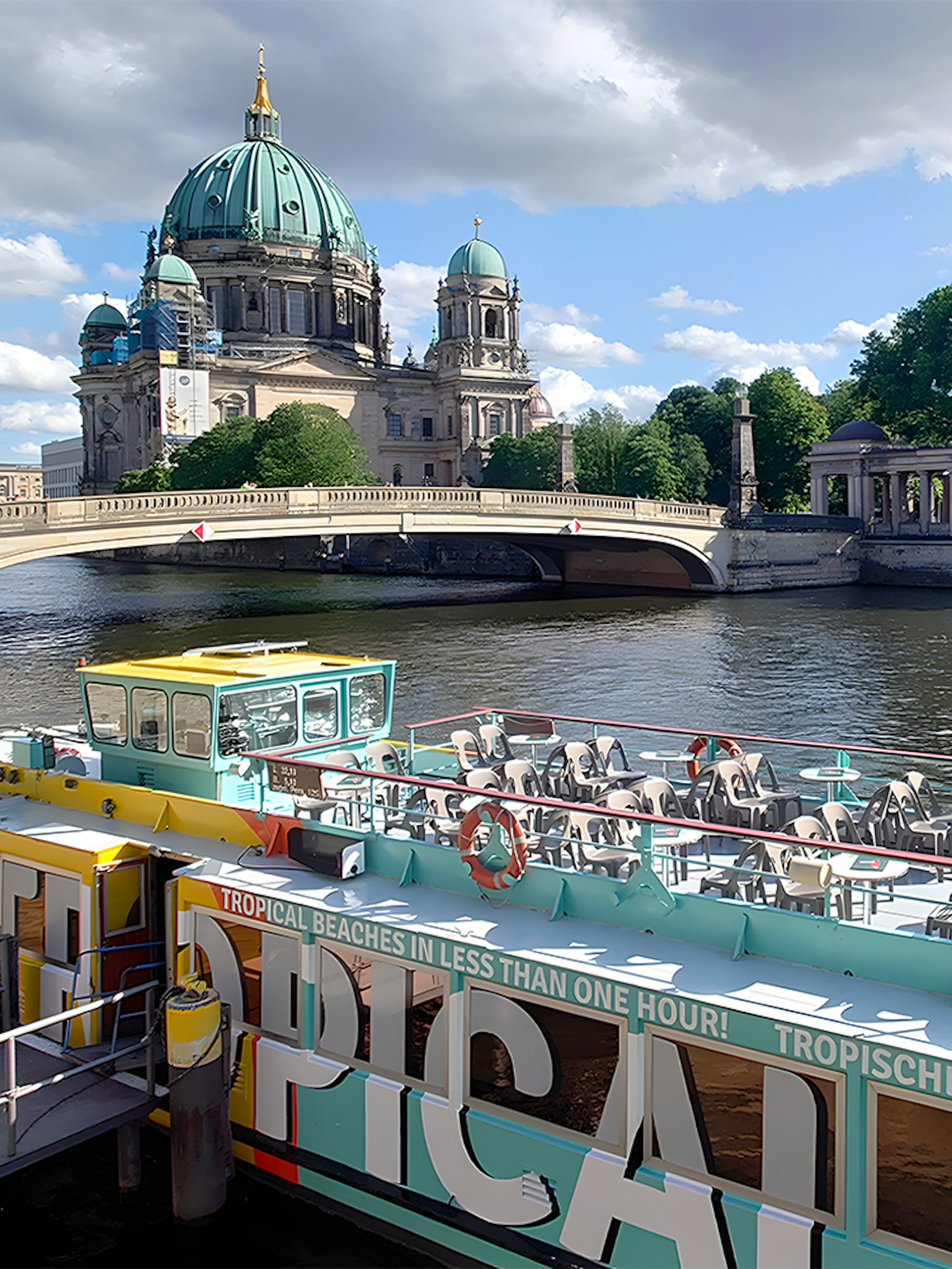 Sightseeing cruise boat on the Spree River with Berlin Cathedral in the background.