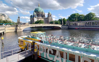 Sightseeing cruise boat on the Spree River with Berlin Cathedral in the background.